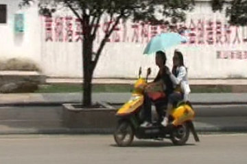 A thoughtful girl keeps the sun off her boyfriend on their daily commute*